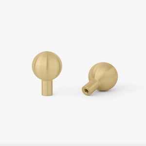 May include: Two gold-toned round cabinet knobs with a smooth, slightly textured surface. The knobs are shown from different angles.
