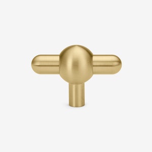 May include: A brushed gold T-shaped cabinet knob with a round, spherical center.