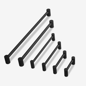 May include: A set of six black metal cabinet pulls in various sizes. The pulls are all cylindrical in shape with rounded ends.