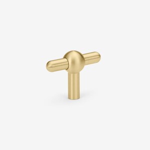 May include: A gold-toned T-shaped cabinet knob with a rounded ball in the center.