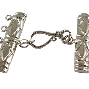 May include: Silver-toned metal clasp with a diamond pattern and four jump rings on each side. The clasp has a hook and loop closure.