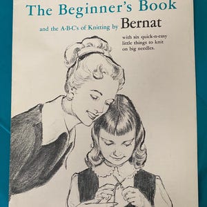 Puede incluir: Un libro de tejido vintage titulado "The Beginner's Book" y el A-B-C del tejido por Bernat. La portada presenta una ilustración en blanco y negro de una mujer enseñando a una niña a tejer.