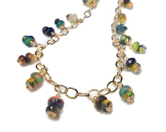 Puede incluir: Un collar de cadena dorada con múltiples cuentas de ópalo en tonos verdes, azules, amarillos y rojos. El collar presenta una cadena delicada y las cuentas de ópalo están agrupadas a lo largo de la cadena.