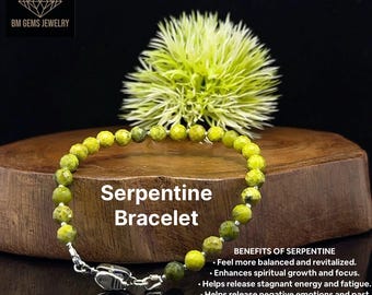 Pode incluir: Uma pulseira de serpentina com fecho prateado. A pulseira apresenta contas redondas verde claro. O texto "Serpentine Bracelet" é exibido na imagem. O fundo inclui uma superfície de madeira e uma planta verde espinhosa.