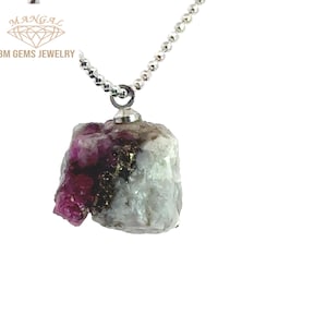 May include: A silver necklace with a pendant made from a rough, uncut gemstone. The pendant features a mix of white, gray, and deep pink colors, with some gold flecks. The necklace is a ball chain style.