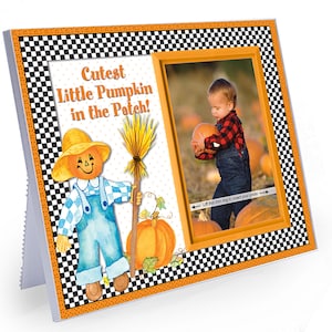 May include: A black and white checkered picture frame with an orange border. The frame has a cutout for a photo and a printed image of a scarecrow holding a broom and a pumpkin. The text "Cutest Little Pumpkin in the Patch!" is printed on the frame. The frame is designed to hold a 4x6 inch photo.