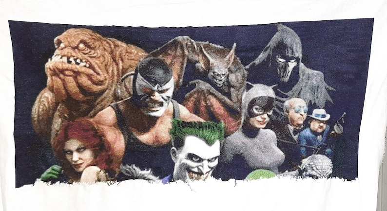 Puede incluir: Un fondo azul oscuro con un grupo de personajes de c&oacute;mics, incluyendo Batman, Joker, Catwoman, Bane y otros. Los personajes est&aacute;n representados en un estilo gr&aacute;fico con colores llamativos y rasgos exagerados.