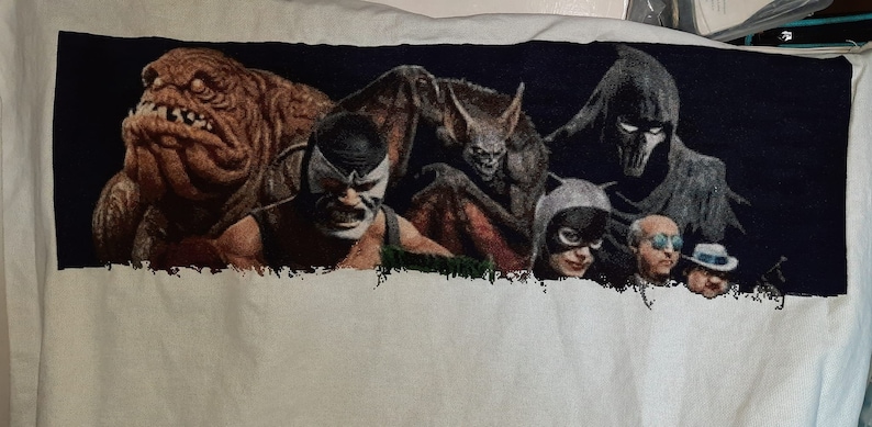 Puede incluir: Bordado de punto de cruz con un grupo de villanos de c&oacute;mics, incluyendo Bane, Man-Bat y el Espantap&aacute;jaros. Los villanos se representan en un entorno oscuro y sombr&iacute;o.