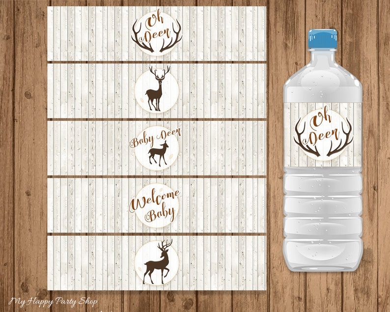 May include: Water bottle with a blue cap and a label that says "Oh Deer" with brown antlers. The image also shows matching water bottle labels with deer and text "Baby Deer" and "Welcome Baby" on a wood grain background.