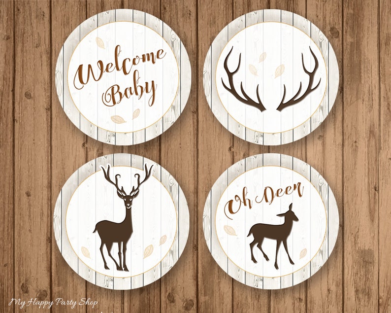 May include: Four circular baby shower decorations with a rustic theme. Each circle has a white wood grain background with brown text and accents. The text includes "Welcome Baby" and "Oh Deer", along with deer and antler silhouettes.