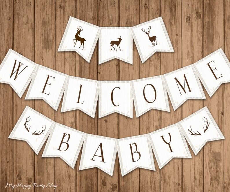 May include: A rustic banner set with the words "WELCOME BABY" in dark brown letters. The banner flags are white with a wood grain texture and brown deer silhouettes. The background is a wooden surface.