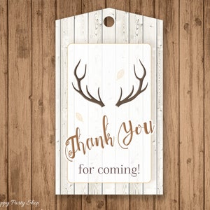 May include: A rustic-themed gift tag with a wooden background. The tag features a white rectangular area with brown antlers and the words "Thank You for coming!" in a decorative font. A small hole is at the top.