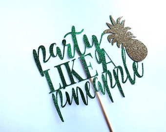 May include: A glittery green and gold pineapple cake topper with the phrase "Party Like a Pineapple." The topper is on a wooden stick, perfect for a tropical-themed party or celebration. The design is set against a white background.