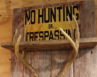 Whitetail deer antler shelf on barn wood with No Hunting or Trespassing sign