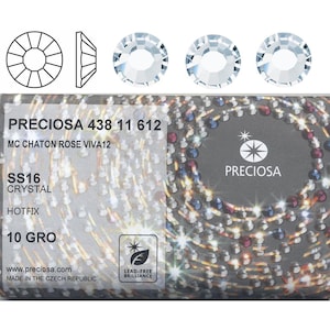 Könnte beinhalten: Nahaufnahme einer Packung PRECIOSA 438 11 612 MC CHATON ROSE VIVA12 SS16 CRYSTAL HOTFIX 10 GRO Strasssteine. Die Verpackung ist silberfarben mit schwarzem Rand und zeigt eine Nahaufnahme der Strasssteine. Der Text "PRECIOSA" ist in Weiß auf der Verpackung gedruckt.
