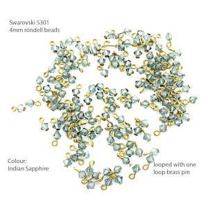May include: A scattering of 4mm light blue Swarovski 5301 rondell beads with gold-toned looped brass pins. The beads are called Indian Sapphire.