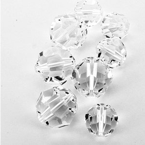 Puede incluir: Un grupo de ocho cuentas redondas facetadas de vidrio transparente. Las cuentas miden aproximadamente 2,5 cm de diámetro y tienen un acabado liso y pulido.