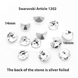 Op de afbeelding: Heldere Swarovski Artikel 1202 kristallen, sommige meten 14 mm en 16 mm. De achterkant van de stenen is zilverfolie. De kristallen zijn rond en facetgeslepen en reflecteren licht. Er zijn ook verschillende halvemaanvormige kristallen aanwezig.