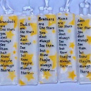 Op de afbeelding: Set van acht glazen bladwijzers met gele stermotieven en inspirerende boodschappen over familie en vrienden. De boodschappen omvatten "Goede vrienden zijn als sterren", "Opa's zijn als sterren", "Vaders zijn als sterren", "Broers zijn als sterren", "Moeders zijn als sterren", "Zonen zijn als sterren", "Zussen zijn als sterren".