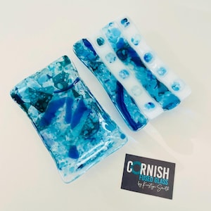 May include: Two blue and white fused glass dishes. The larger dish is rectangular and has a mottled blue and white design. The smaller dish is a long rectangle with white stripes and blue dots.