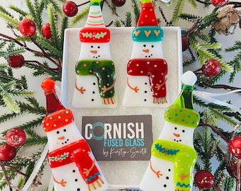 Könnte beinhalten: Set aus vier handgefertigten gläsernen Schneemann-Anhängern. Jeder Schneemann trägt einen Hut und einen Schal in einer anderen Farbe. Die Anhänger sind mit weißem, rotem, grünem und blauem Glas verziert. Die Anhänger sind mit "Cornish Fused Glass by Kirsty Smith" beschriftet.