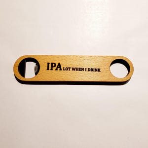 May include: Wooden bottle opener with a metal opener on one end and a hole on the other end. The opener has the text "IPA LOT WHEN I DRINK" engraved on it.