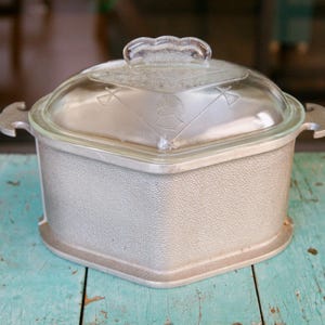 May include: A silver, octagonal-shaped baking dish with a glass lid. The dish has a textured surface and the lid has a raised design.