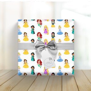 Pu&ograve; includere: Carta da regalo bianca con un motivo ripetitivo di principesse Disney in varie pose. Le principesse indossano i loro abiti caratteristici e hanno i capelli acconciati in modo iconico. La carta &egrave; legata con un nastro argentato e un cartellino regalo che dice "Millie V Designs".