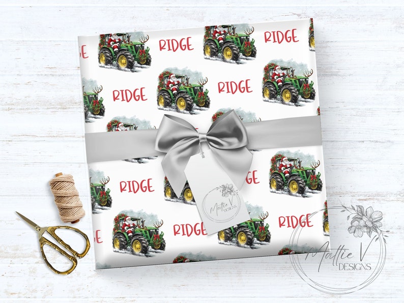 May include: White wrapping paper with a repeating pattern of a green tractor pulling a Christmas tree with Santa Claus driving. The text 'RIDGE' is repeated in red on the wrapping paper. The wrapping paper is tied with a silver ribbon and bow.