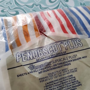K&ouml;nnte beinhalten: Eine Packung Penobscot Plus Doppelbettlaken. Die Bettlaken haben ein gestreiftes Muster in Rot, Wei&szlig;, Blau und Orange. Die Verpackung enth&auml;lt Text &uuml;ber die Fadenzahl und die Abmessungen der Laken (206 x 244 cm).