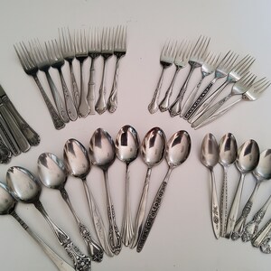 May include: A set of silverware with ornate handles. The set includes forks, spoons, and knives, all made of stainless steel.