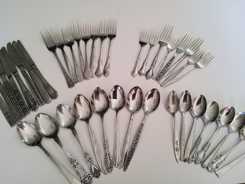 May include: A set of silverware with ornate handles. The set includes forks, spoons, and knives, all made of stainless steel.