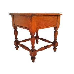 May include: A small, antique wooden side table with a warm, reddish-brown finish. The table features a rectangular top, a single drawer, and ornate, turned legs connected by a lower stretcher. The table is a classic piece of furniture.