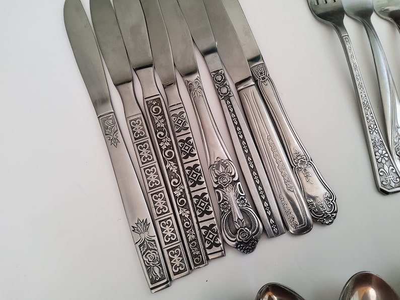 May include: A set of silver knives with intricate floral and geometric designs etched into the handles.
