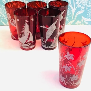 May include: Set of six red glass tumblers with etched designs. The designs include a sailboat, a bird, and flowers.