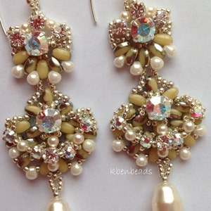 May include: A pair of delicate, cream-colored beaded earrings with a pearlescent drop. The earrings feature a cluster of crystals and beads in a floral design. The text "Nadia earrings" and "A pdf tutorial by Karen Beningfield" are visible in the image.