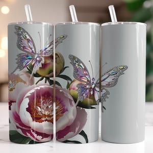 Puede incluir: Tres vasos de acero inoxidable con fondo gris y un diseño de peonías rosas y mariposas adornadas con joyas.