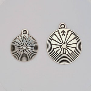 May include: Two silver pendants with a circular design featuring a concentric circle pattern and a symbol in the center. The larger pendant is about 2 inches in diameter, while the smaller pendant is about 1 inch in diameter.