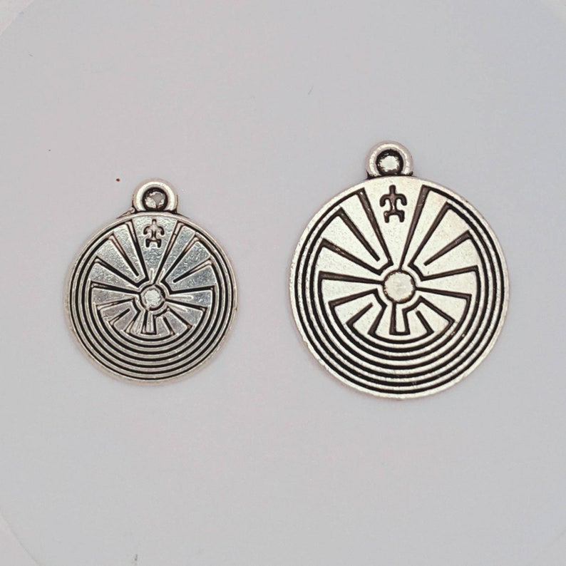 May include: Two silver pendants with a circular design featuring a concentric circle pattern and a symbol in the center. The larger pendant is about 2 inches in diameter, while the smaller pendant is about 1 inch in diameter.