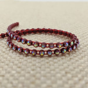 May include: Two strands of red trim with iridescent rhinestones. The trim is made of plastic and is perfect for adding a touch of sparkle to crafts.