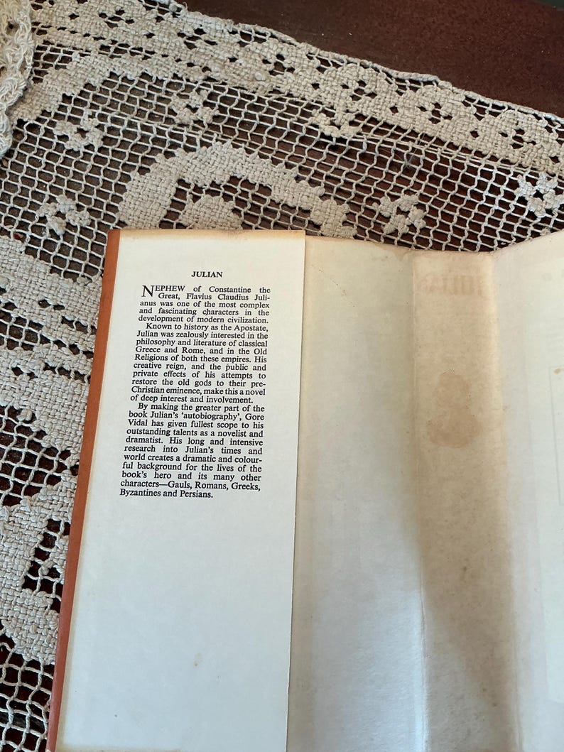 Puede incluir: Libro abierto con el t&iacute;tulo "JULIAN". El texto describe la vida de Julian y su contexto hist&oacute;rico, incluyendo su inter&eacute;s en la Grecia y Roma cl&aacute;sicas. El lomo del libro es naranja y las p&aacute;ginas son blanquecinas.