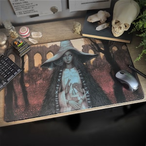May include: A rectangular mousepad featuring a gothic illustration of a woman in a wide-brimmed hat and cloak, holding a bell. The artwork is set against a backdrop of a dark forest and arched structures, with a keyboard and mouse visible.
