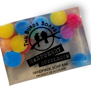 Peut inclure: Un savon transparent parfum&eacute; &agrave; la framboise et au chewing-gum. Le savon est d&eacute;cor&eacute; de p&eacute;pites rondes color&eacute;es et porte l'inscription "Two Birds Soaps" et "Raspberry Bubblegum" en lettres noires. Le savon est fait &agrave; la main en &Eacute;cosse.