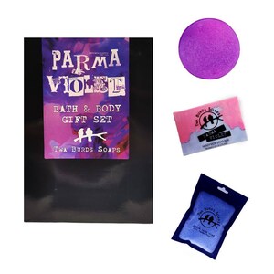 May include: A black gift box with the text "Parma Violet Bath & Body Gift Set" and the logo "Twa Burds Soaps". The box contains a purple bath bomb, a pink and blue handmade soap bar, and a blue soap bar.