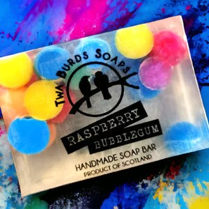 Peut inclure: Une barre de savon transparente au parfum de bubble-gum &agrave; la framboise. La barre de savon est d&eacute;cor&eacute;e de morceaux de savon ronds color&eacute;s. La barre de savon est emball&eacute;e dans une pellicule plastique transparente avec une &eacute;tiquette noire qui indique "Twa Birds Soaps Raspberry Bubblegum Handmade Soap Bar Product of Scotland".