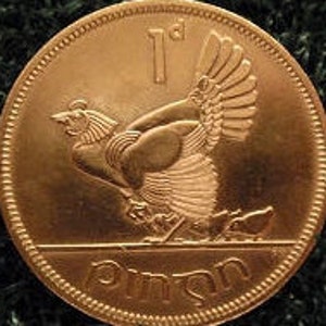May include: A copper-colored coin with a depiction of a stylized bird with its wings spread. The coin has the inscription "1d" and "Píosa" on it.