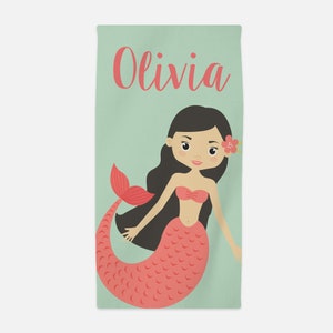 May include: A rectangular beach towel featuring a light green background with the name Olivia printed in coral pink script. The towel displays a cartoon mermaid with long dark hair, a coral pink tail, and a small flower tucked behind her ear.