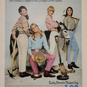 May include: Vintage advertisement for Lee Lady Stretch Riders jeans. The image features four women in the jeans, posing with tools and a donkey. The text reads "Slide into a pair of Lady Stretch Riders and look like you just staked a claim to the Cripple Creek Lode."