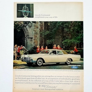 May include: Vintage advertisement for a Lincoln Continental car. The image features a cream-colored sedan with a tan roof, parked in front of a building. People in red coats are standing near the car. Text includes "Lincoln Continental compliments your way of life."
