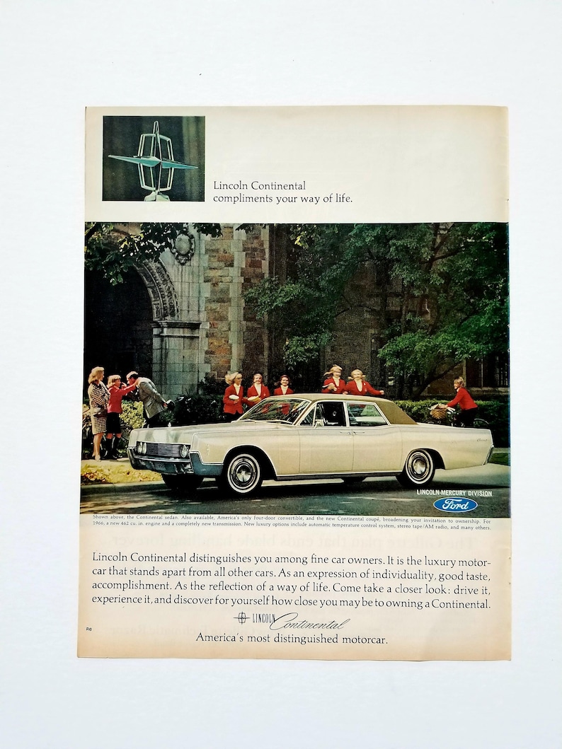 May include: Vintage advertisement for a Lincoln Continental car. The image features a cream-colored sedan with a tan roof, parked in front of a building. People in red coats are standing near the car. Text includes "Lincoln Continental compliments your way of life."